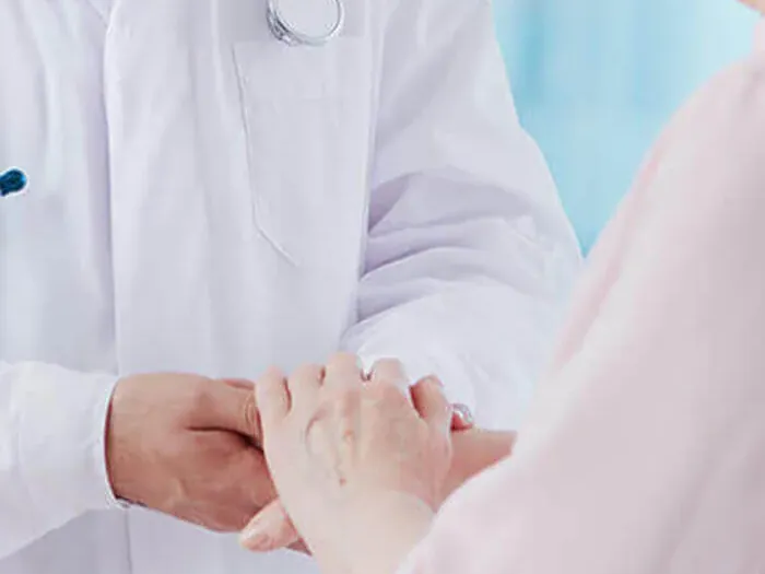 Un médico toma las manos de una paciente mayor